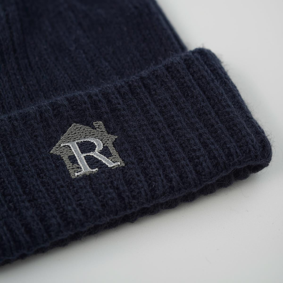 Navy blue knit beanie with a logo on a light gray background